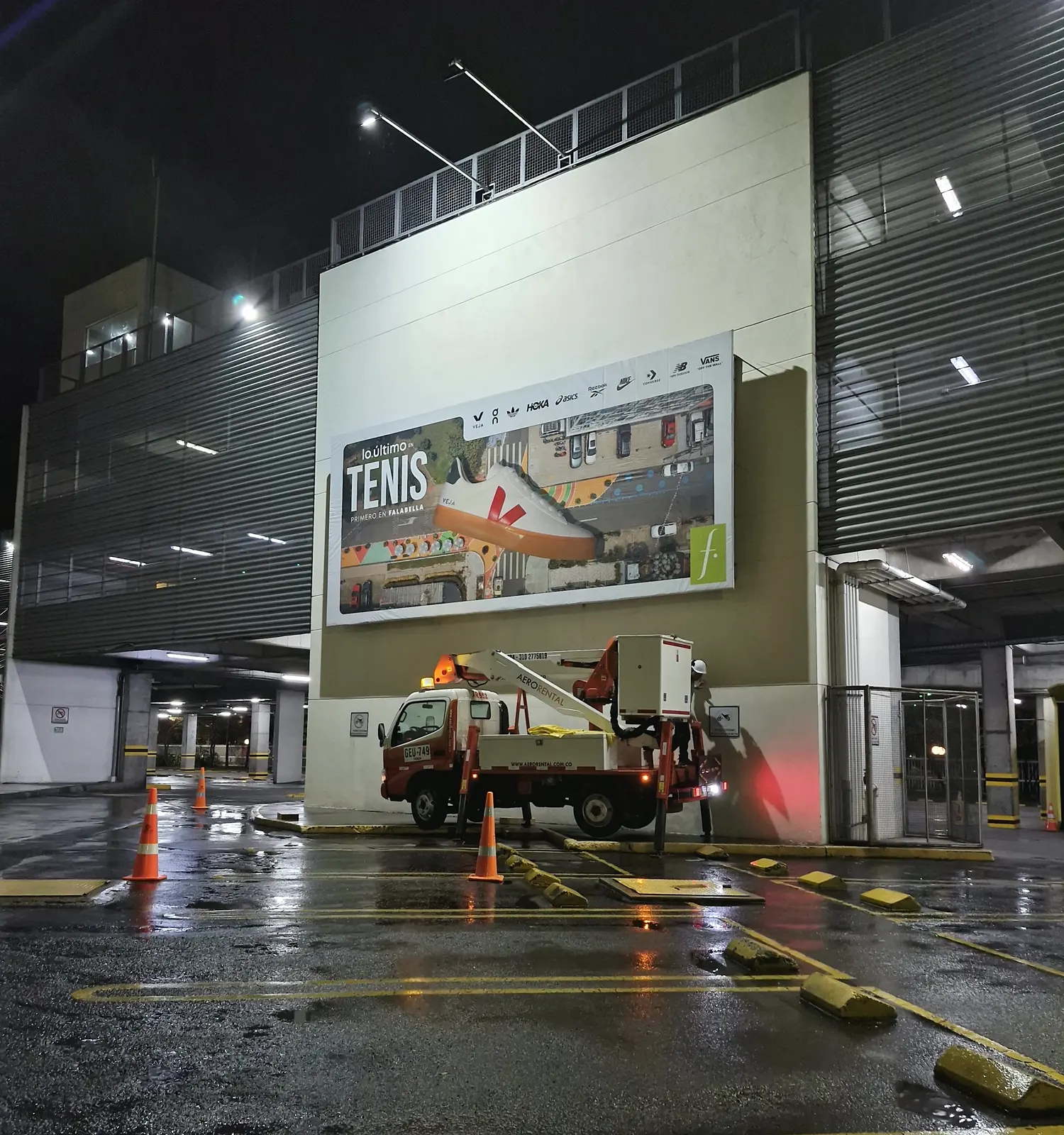 Valla nueva «Lo último en tenis, primero en Falabella» instalada de noche en la fachada del parqueadero de C. C. Unicentro