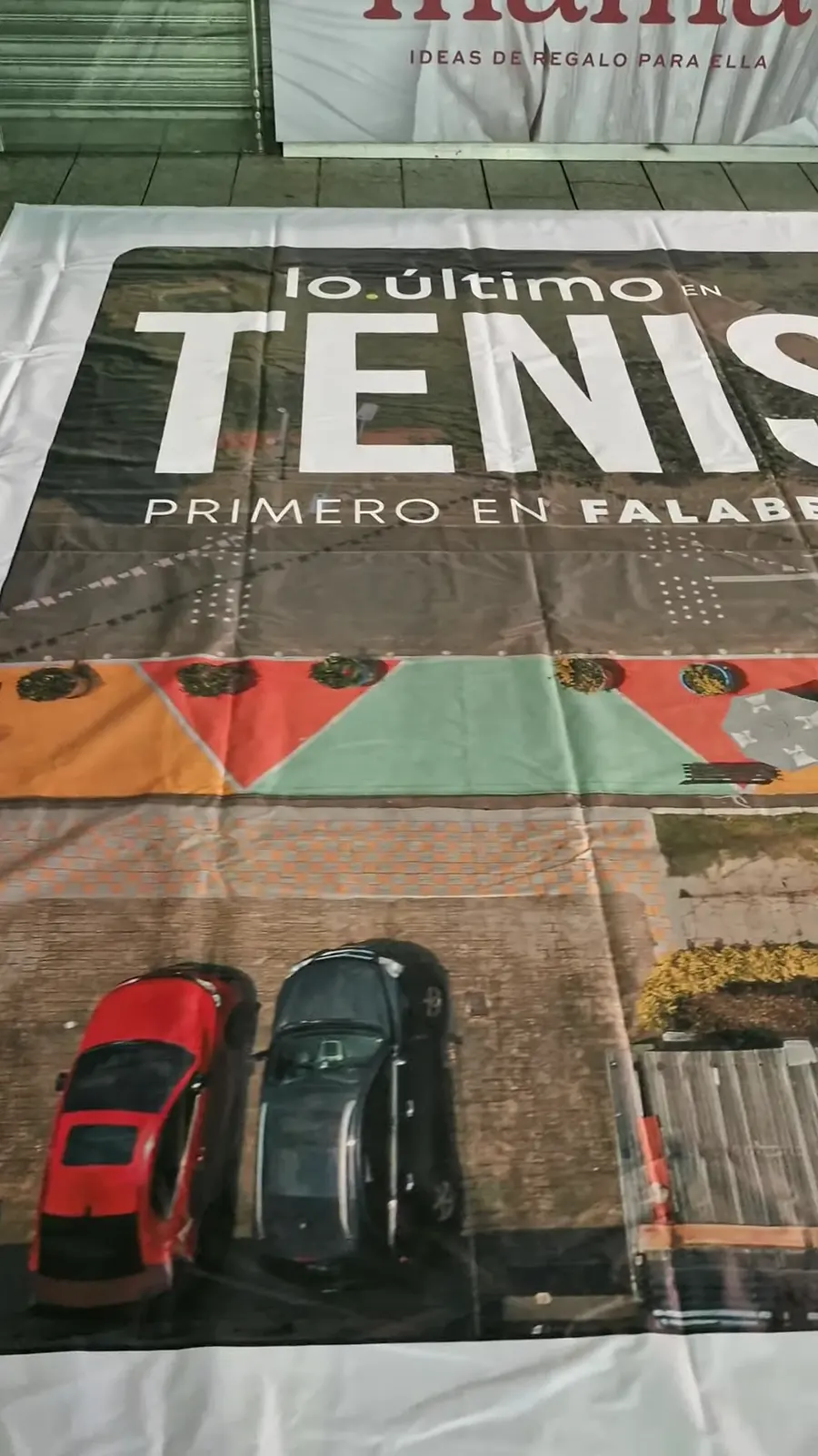 Lona de la valla extendida en el piso antes de subirla, con el texto Lo último en tenis, primero en Falabella