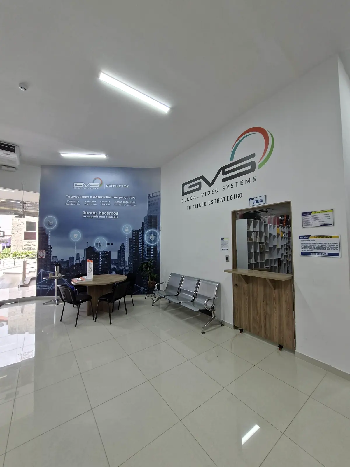 Recepción de GVS con el logo 'Global Video Systems, tu aliado estratégico' en la pared y un mural de ciudad en vinilo junto a la sala de espera