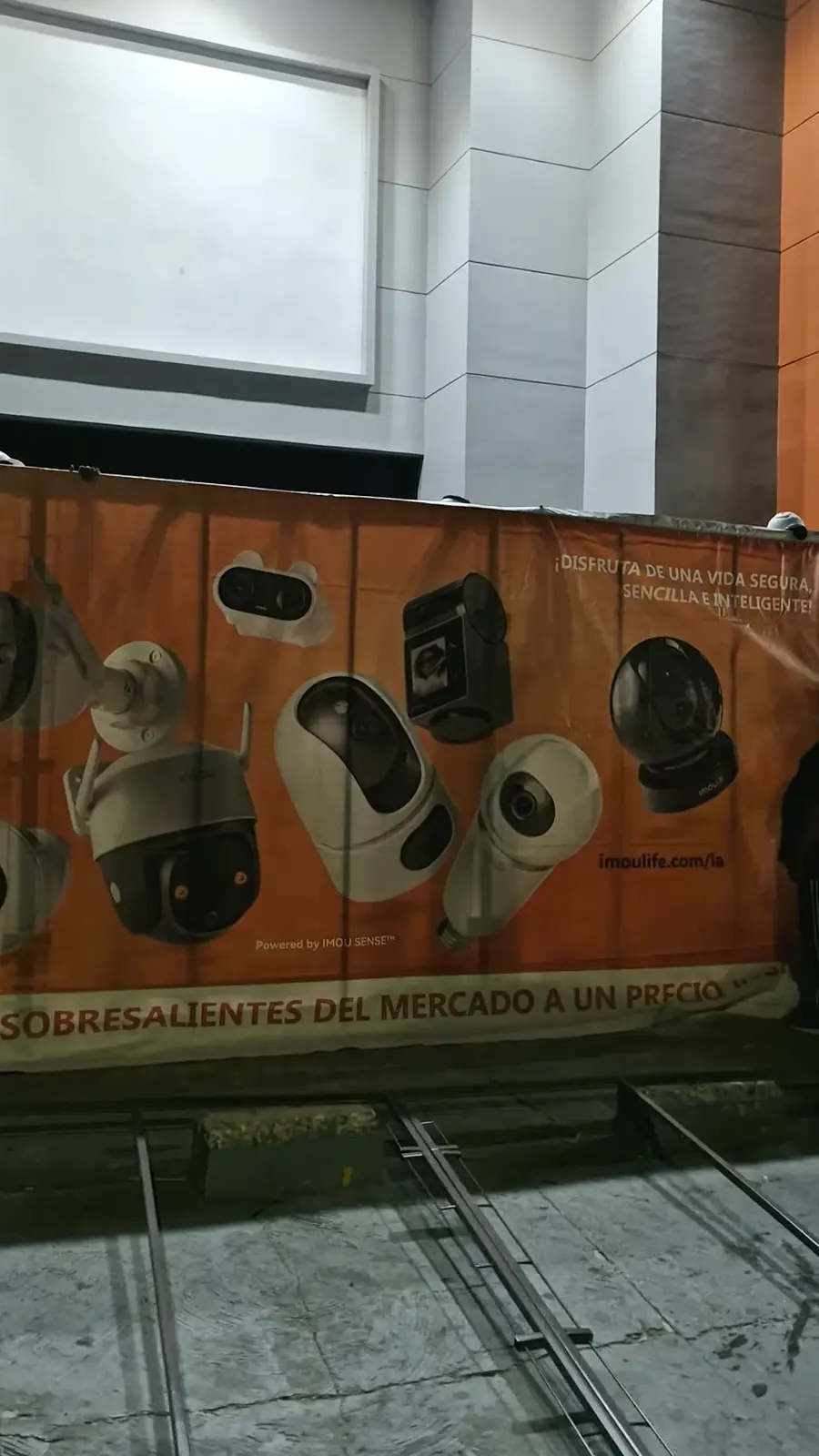 Valla naranja de cámaras Imou tensada en su bastidor durante el montaje nocturno frente a la sede GVS