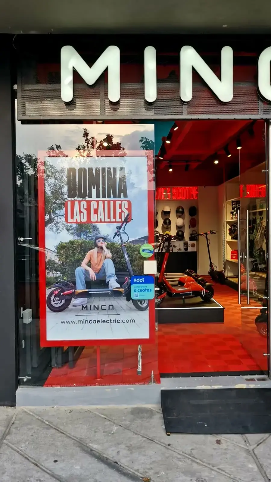 Fachada de la tienda Minca con el tótem rojo “Domina las calles” en la vitrina, junto a la entrada
