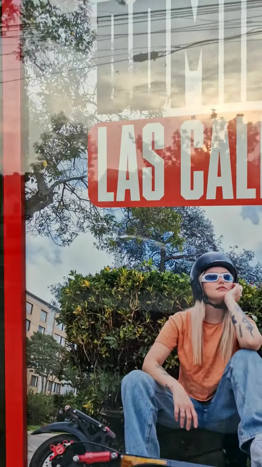 Detalle de la gráfica “Domina las calles” vista a través del vidrio de la vitrina, con una joven y su patineta