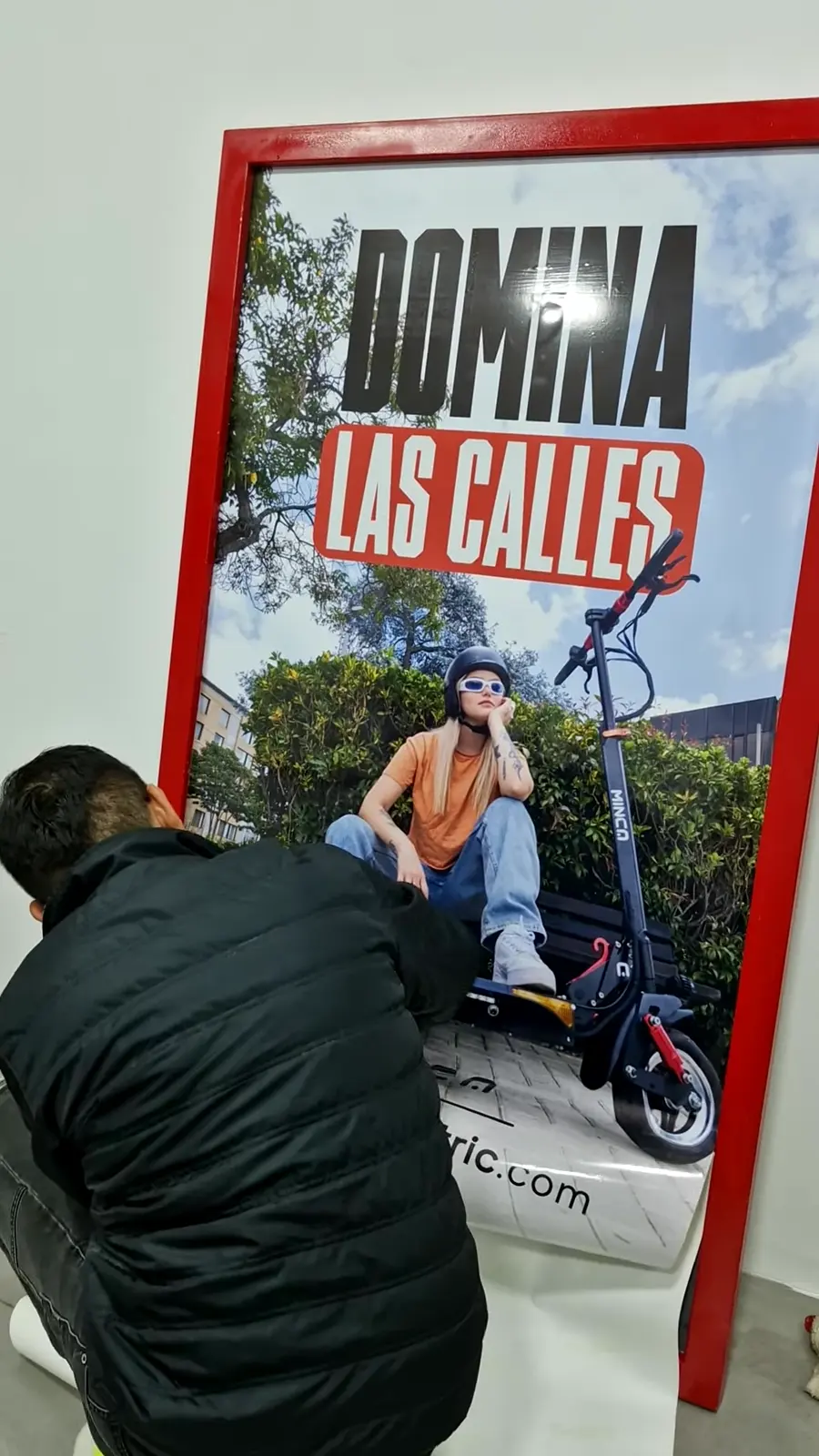 Instalador aplica con espátula la gráfica de Minca sobre el panel del tótem