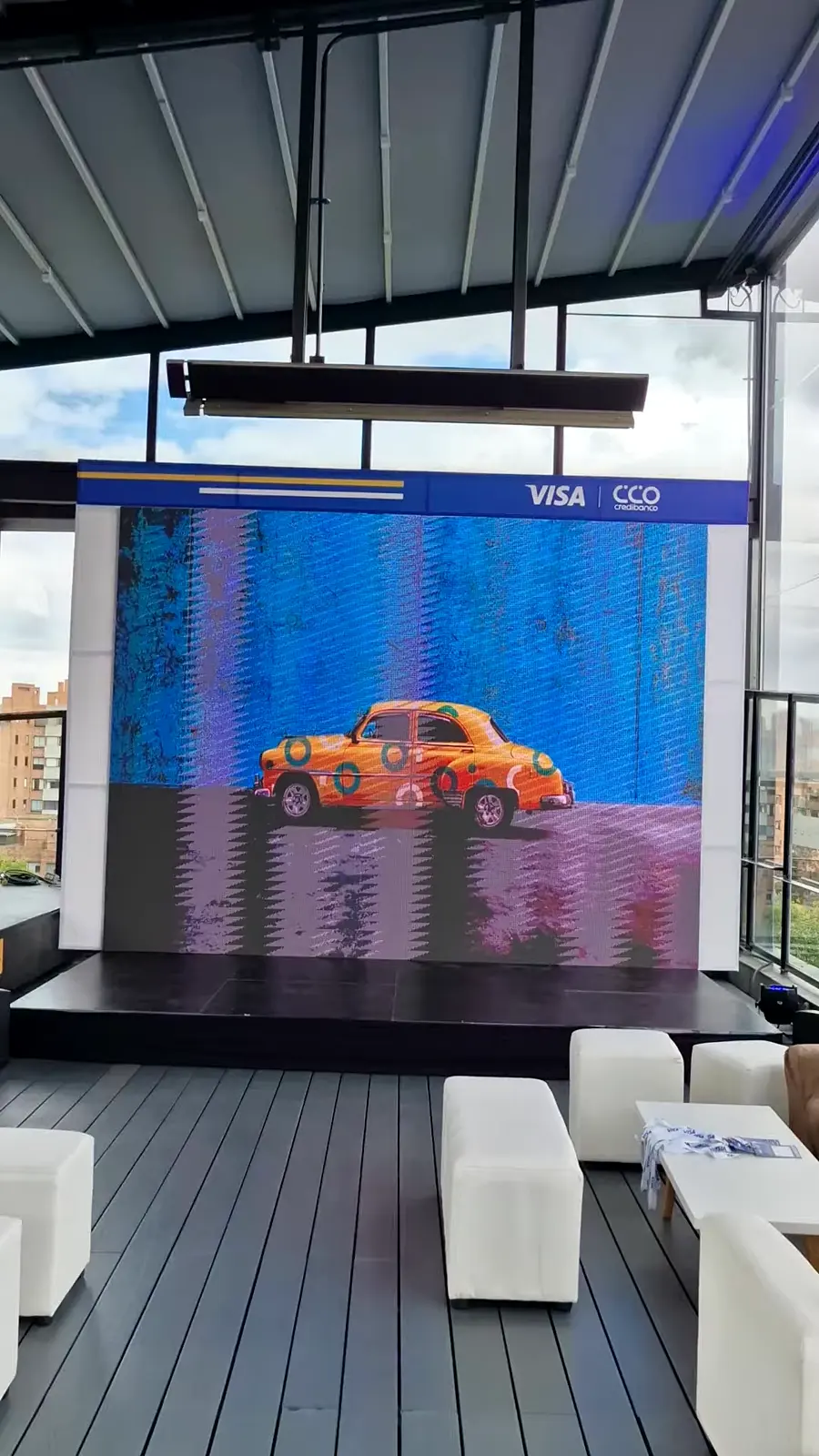 Pantalla LED sobre tarima enmarcada por el arco blanco con cabezote azul y logos de Visa y Credibanco