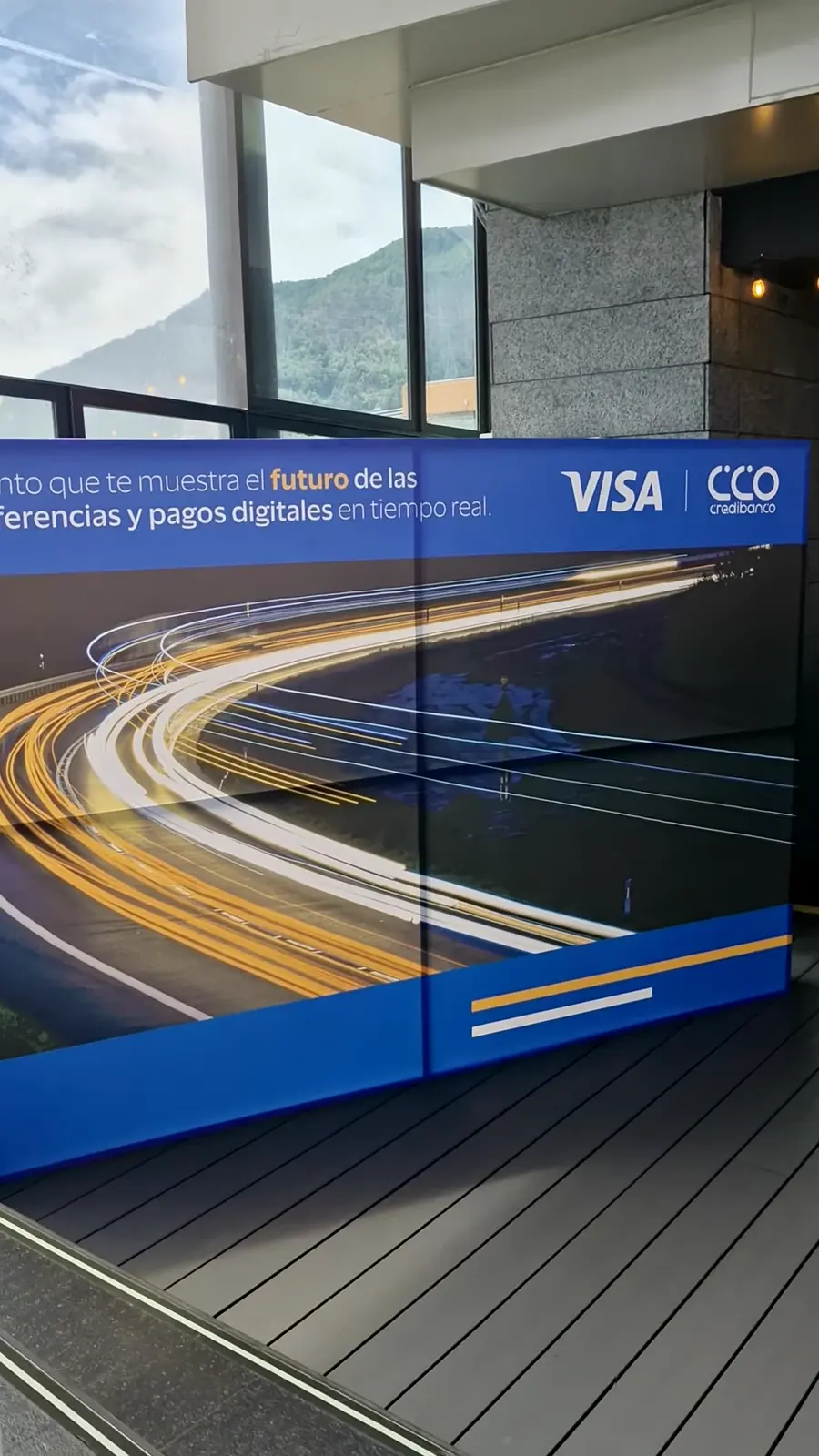 Backing de gran formato de Visa y Credibanco de día, con montañas al fondo tras el vidrio