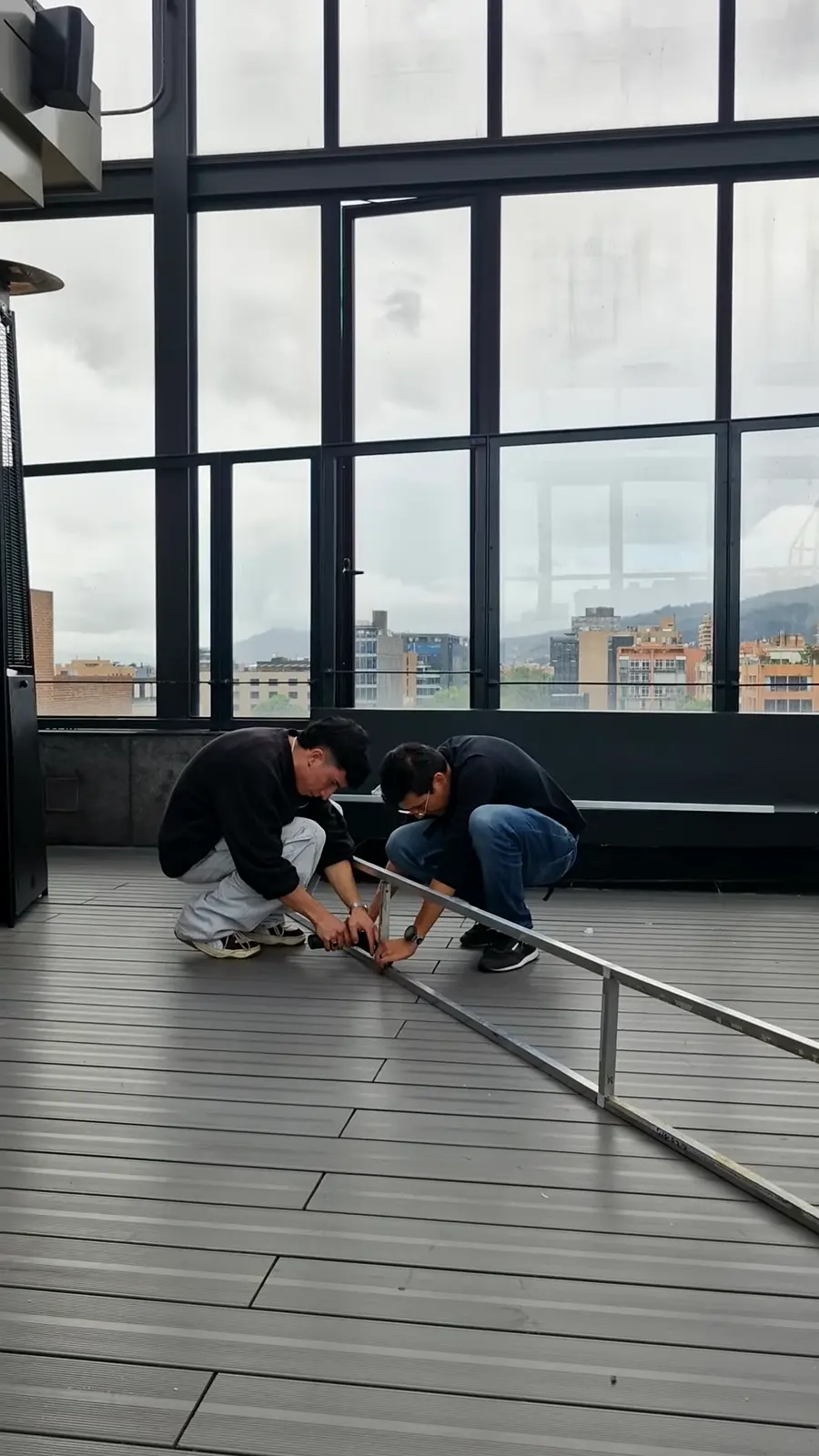 Dos montajistas arman una estructura metálica en el piso de la terraza